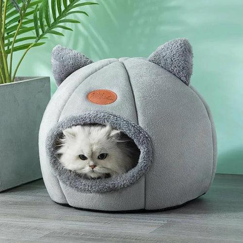 White Persian cat inside cozy cave bed with ears